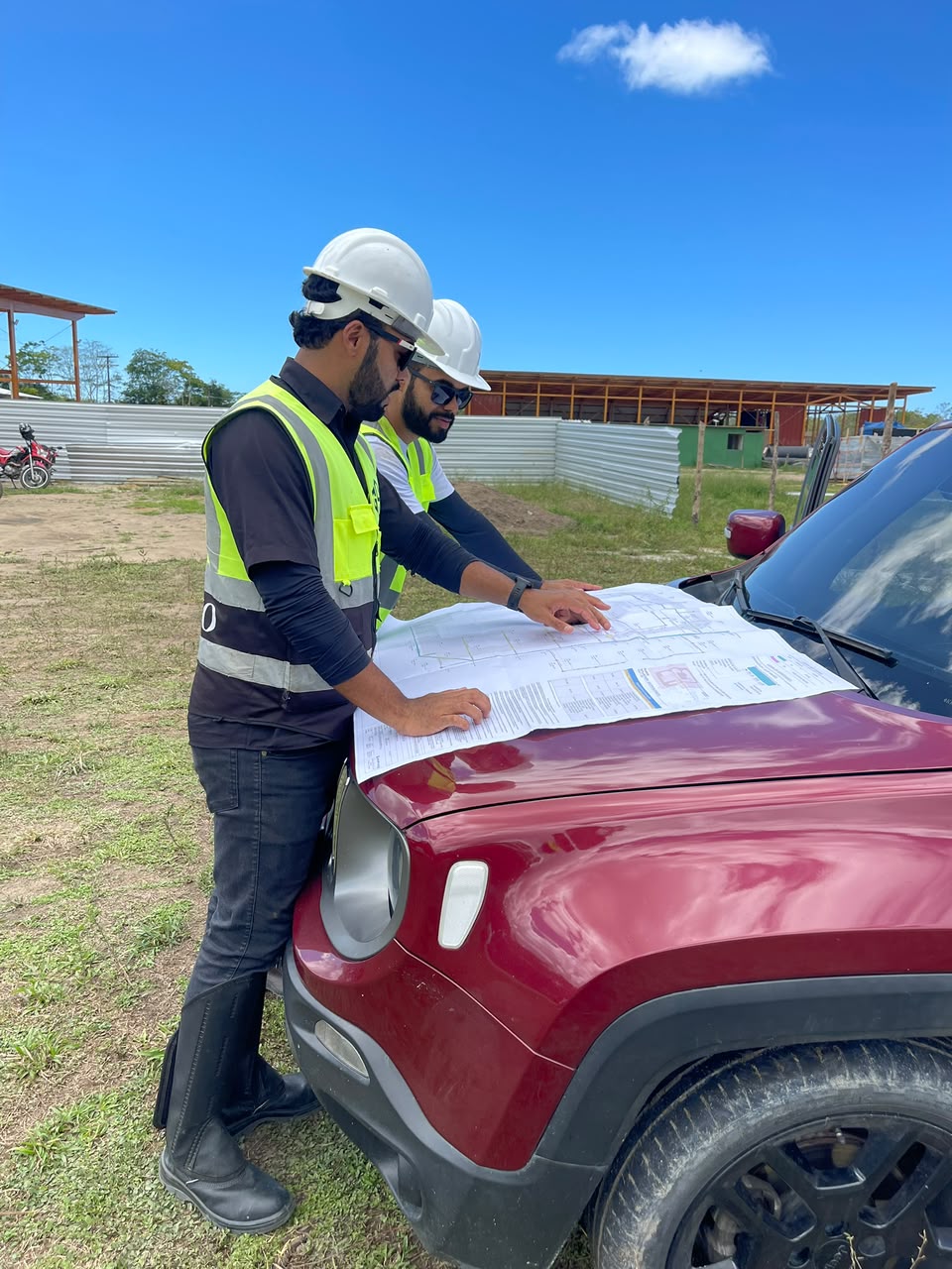 Equipe analisando projeto topográfico em campo