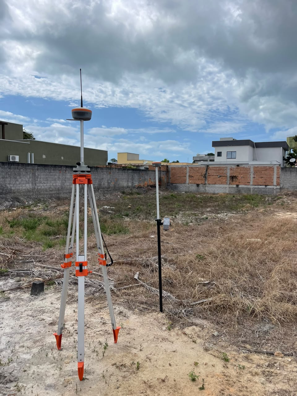 Receptor GNSS e tripé em levantamento de terreno